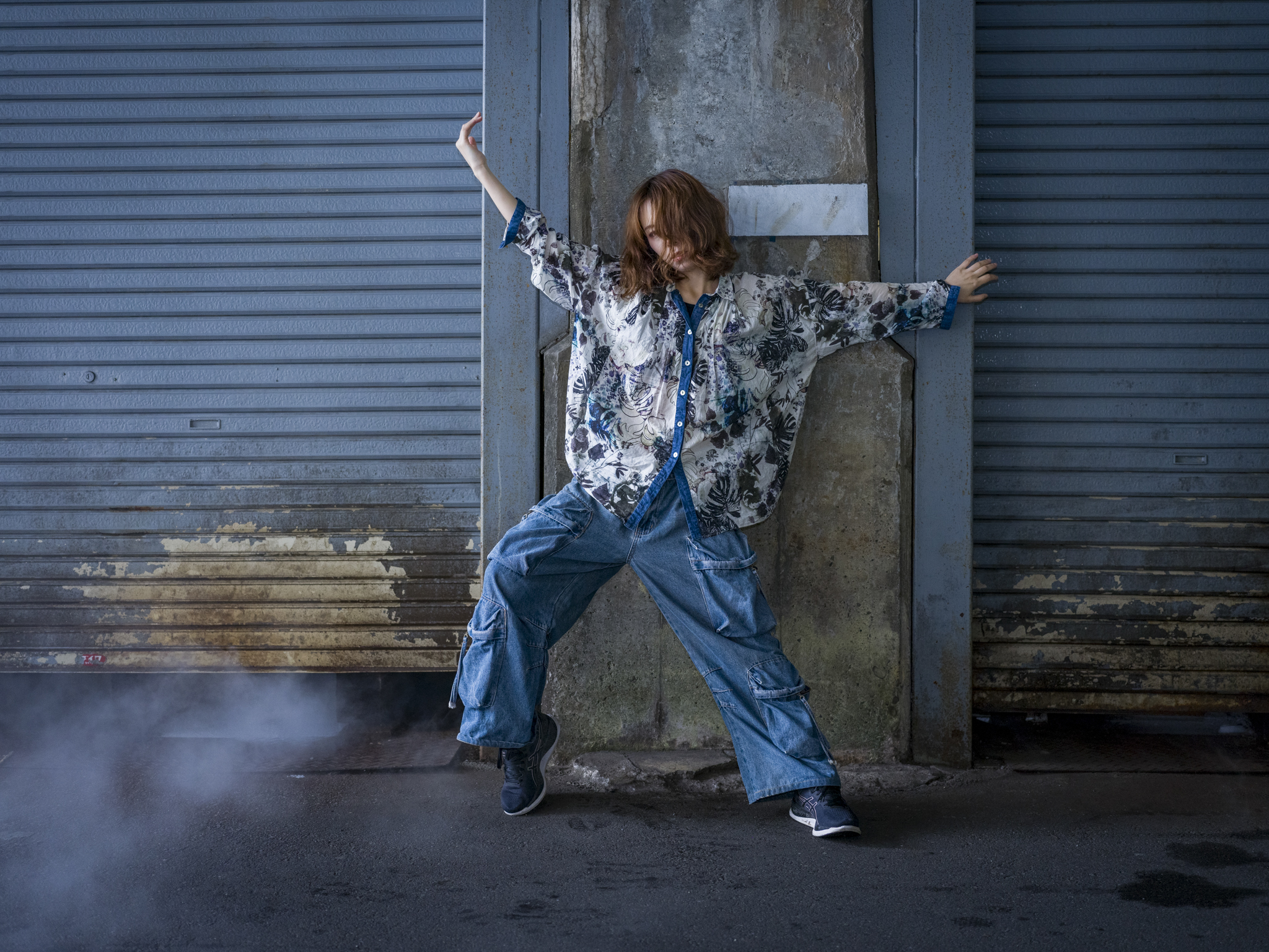 Japanese model Koishi showcasing personal street style wardrobe choices within a moody, industrial urban landscape during a rainy-day fashion editorial around Hankyu Nakatsu Station in Osaka.