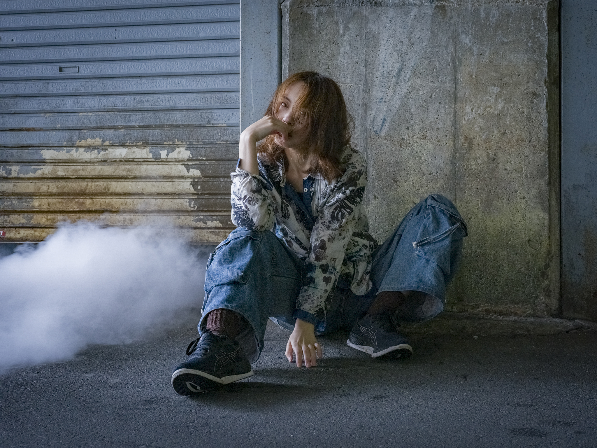 Japanese model Koishi showcasing personal street style wardrobe choices within a moody, industrial urban landscape during a rainy-day fashion editorial around Hankyu Nakatsu Station in Osaka.