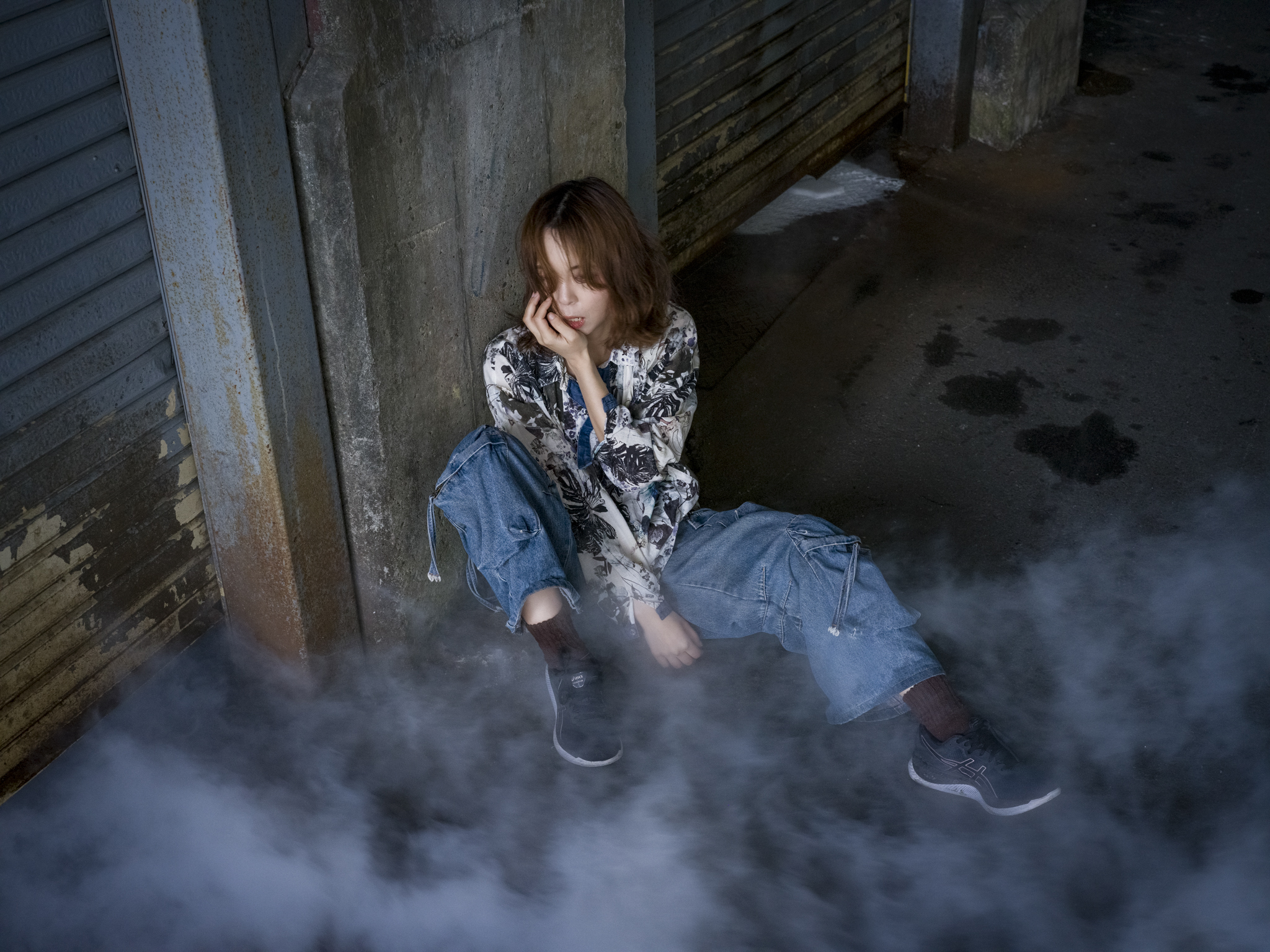 Japanese model Koishi showcasing personal street style wardrobe choices within a moody, industrial urban landscape during a rainy-day fashion editorial around Hankyu Nakatsu Station in Osaka.