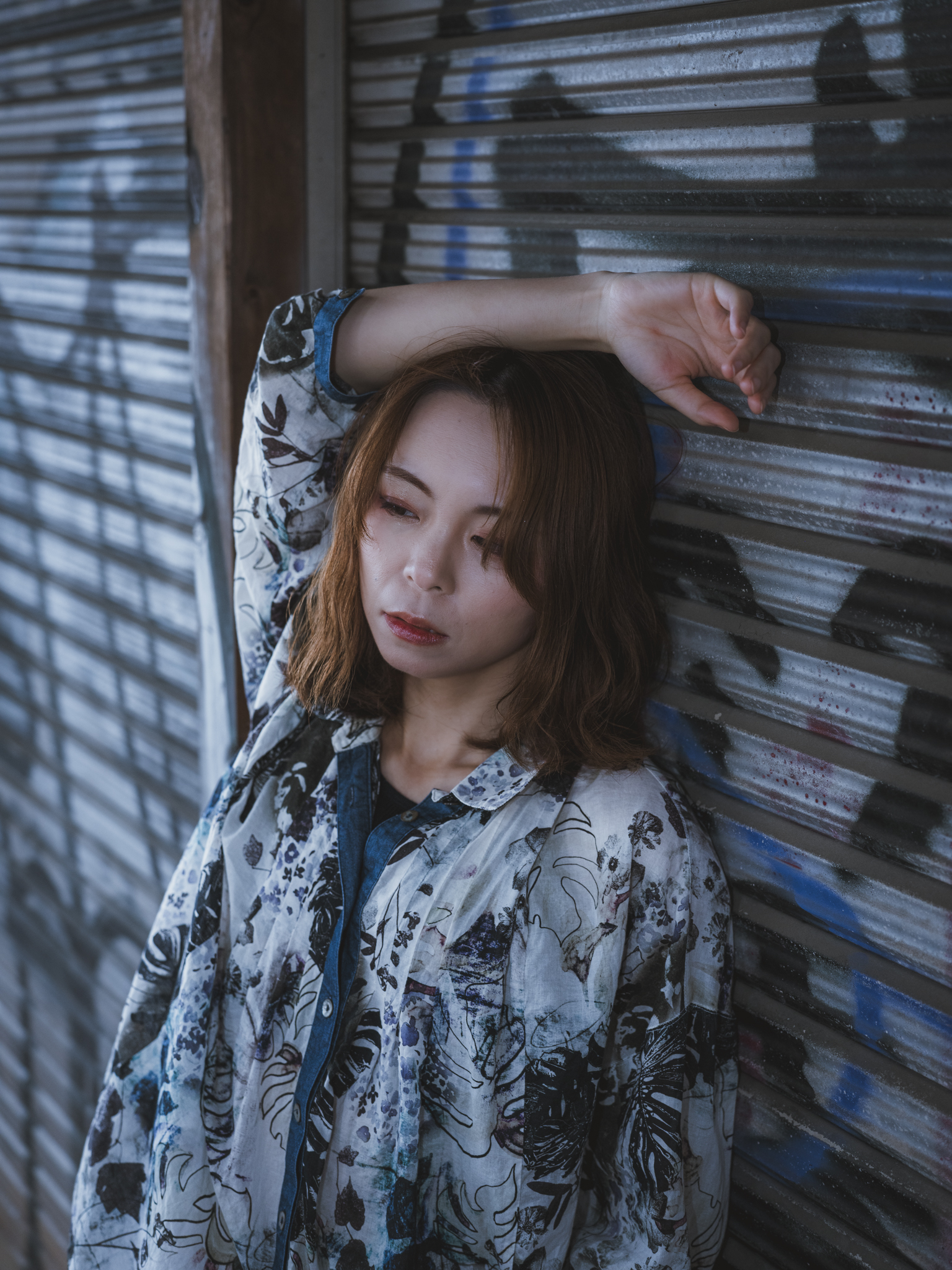 Japanese model Koishi showcasing personal street style wardrobe choices within a moody, industrial urban landscape during a rainy-day fashion editorial around Hankyu Nakatsu Station in Osaka.