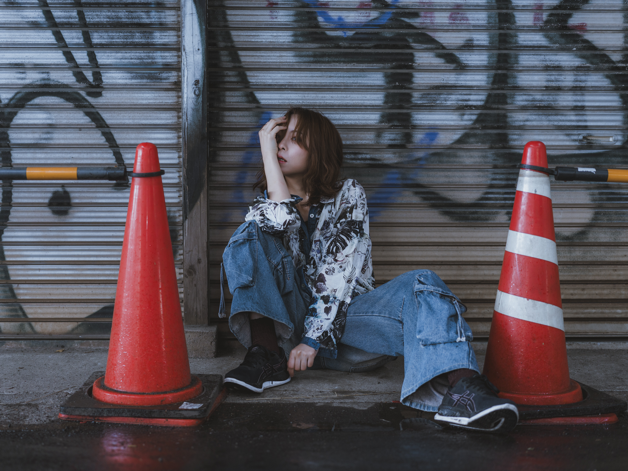 Japanese model Koishi showcasing personal street style wardrobe choices within a moody, industrial urban landscape during a rainy-day fashion editorial around Hankyu Nakatsu Station in Osaka.