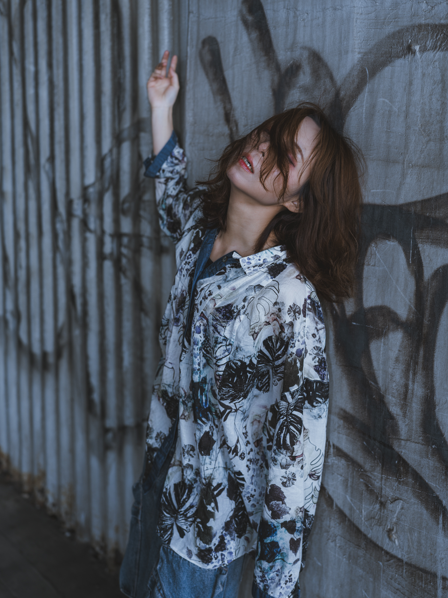 Japanese model Koishi showcasing personal street style wardrobe choices within a moody, industrial urban landscape during a rainy-day fashion editorial around Hankyu Nakatsu Station in Osaka.