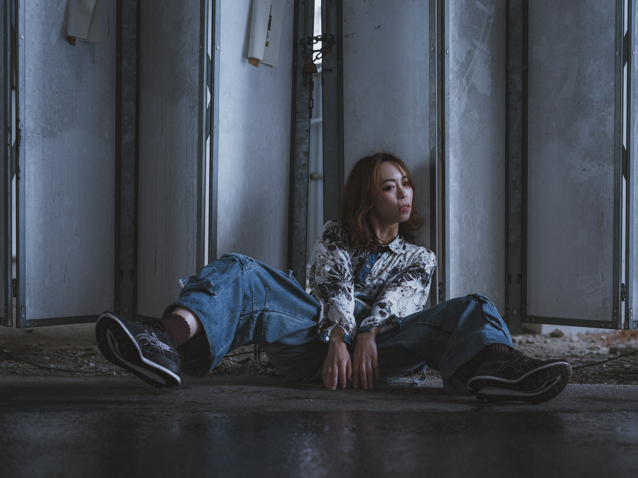 Japanese model Koishi showcasing personal street style wardrobe choices within a moody, industrial urban landscape during a rainy-day fashion editorial around Hankyu Nakatsu Station in Osaka.